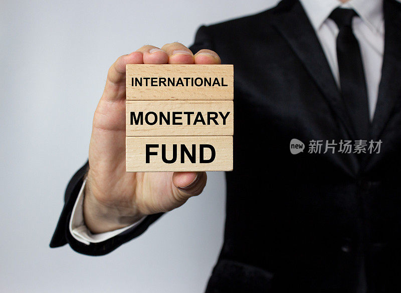 IMF，国际货币基金组织，是写在一块木块上的，在一名西装革履的男子手中。