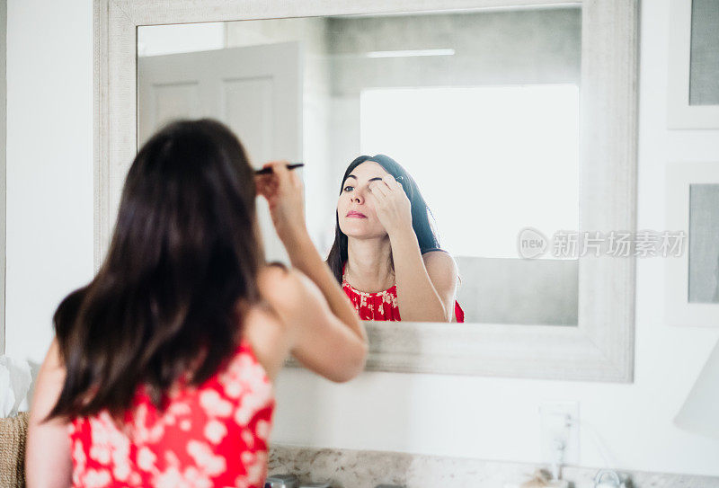 迷人的女人在她的三十多岁在家里的浴室化妆