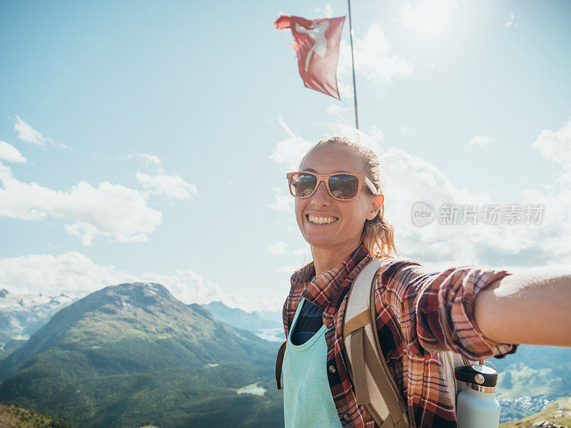一名年轻女子在山顶用瑞士国旗自拍