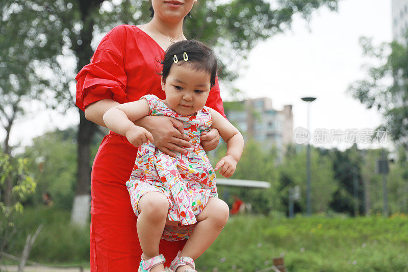 一个中国女孩被她妈妈在公园里抱着