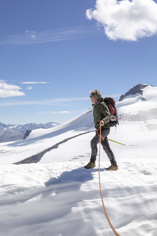 一位男性登山运动员到达了雪山的顶峰