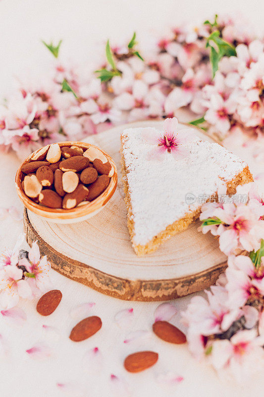 令人愉快的马略卡岛杏仁蛋糕，名字是Gató，木片上装饰着杏仁花和一小碗新鲜的碎杏仁