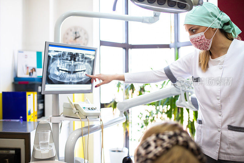 一名女牙医在数码牙科x光片上向病人展示一颗水平智齿