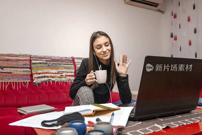 一个十几岁的女孩在网上上课的时候喝着咖啡