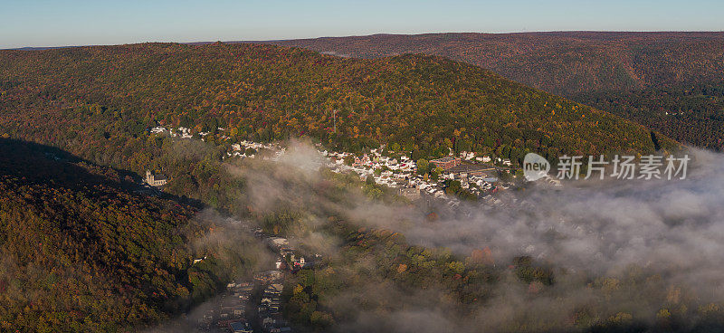 五彩缤纷的秋日里，波科诺山上阳光明媚的清晨，低云笼罩着宾夕法尼亚州历史小镇吉姆·索普。高分辨率航空全景。