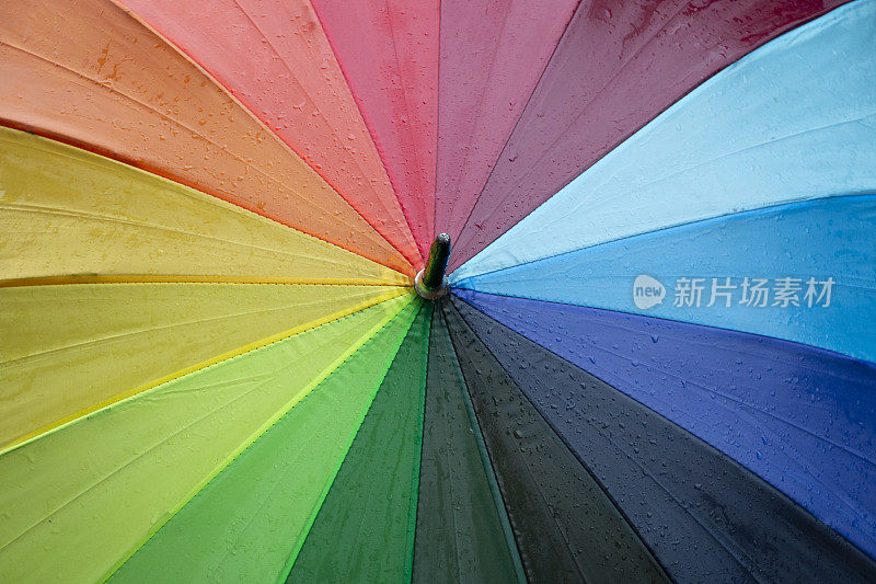雨点落在彩虹伞上，天以自然为背景
