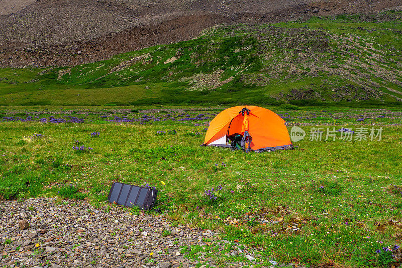营地的太阳能电池。独自徒步在风景如画的夏季山脉。夏季在绿色岩石高原露营。