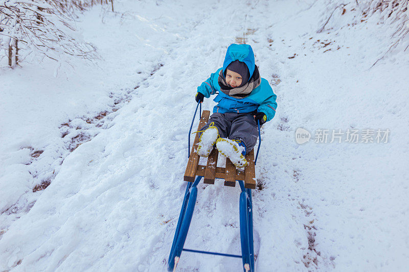 一个白人小男孩坐在雪橇上