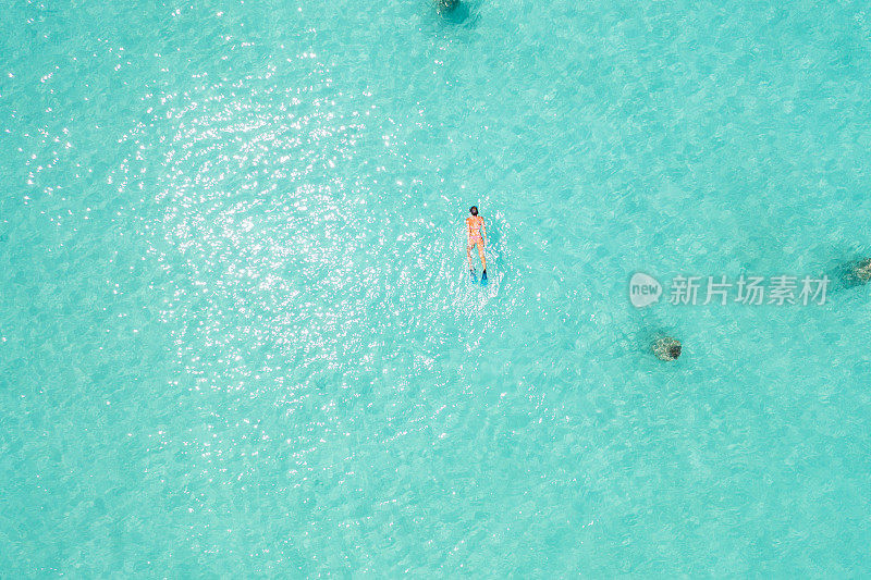 用无人机拍摄的马尔代夫热带蓝色泻湖上的女子浮潜