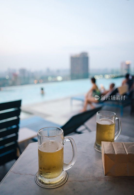 享受放松周五的一杯啤酒在曼谷的屋顶酒吧与游泳池的观点