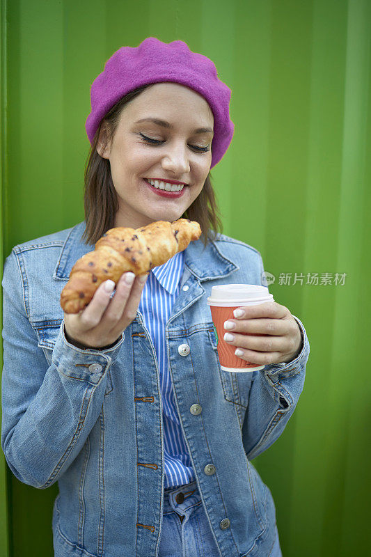 女人咬牛角面包户外酒吧早餐