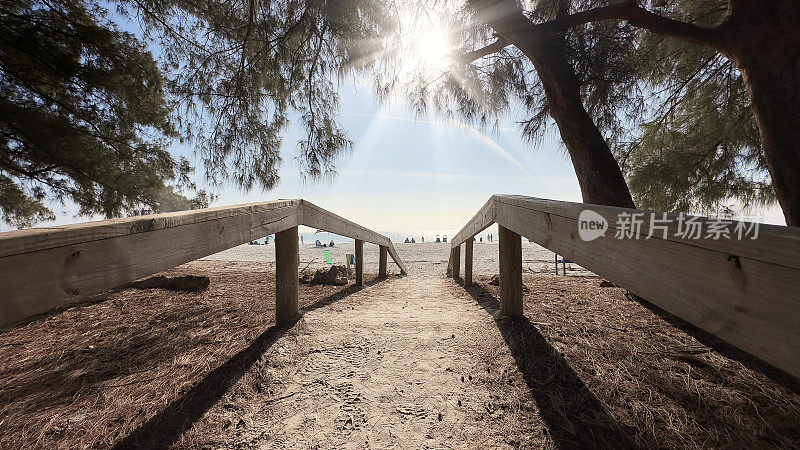 热带沙质岛屿海滩的步道和阳光明媚的蓝天上的沙滩伞