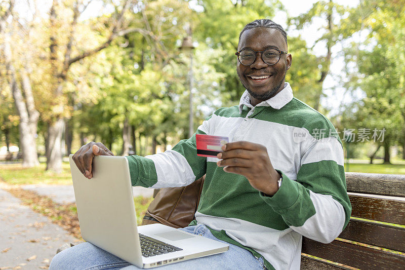 一名男子微笑着用笔记本电脑和信用卡在网上购物