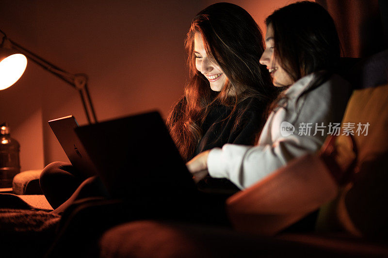 两个十几岁的女孩看着笔记本电脑屏幕