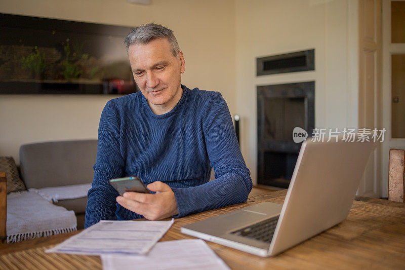 成熟的男人在计算账单和家庭财务时使用计算器