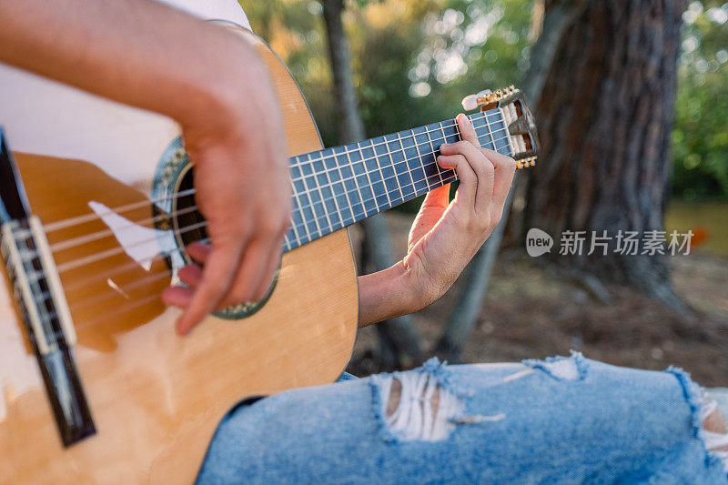 吉他手弹奏吉他。专业吉他手在户外演奏吉他。音乐家在公园里弹古典吉他。音乐家演奏手的特写。