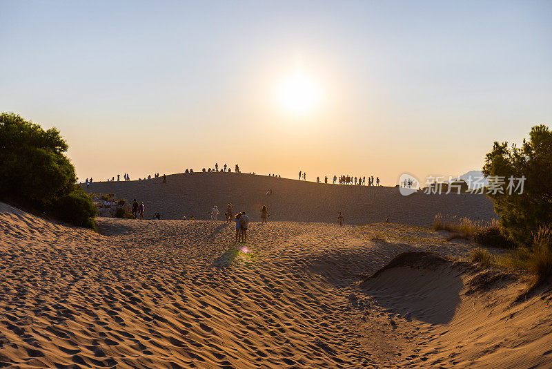 人们在沙丘上观看日落