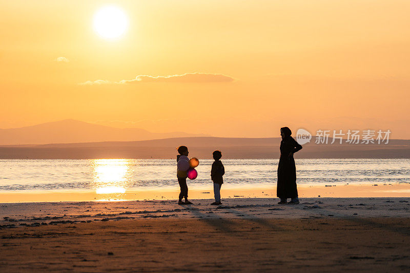 日落时分，母亲与孩子们在海滩上共度时光