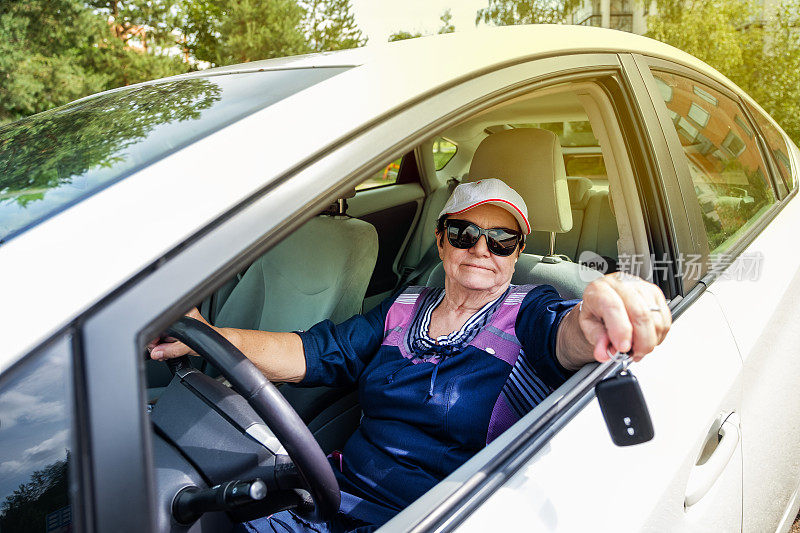 白人老妇，77岁，开着车。这个女人手里拿着车钥匙。
