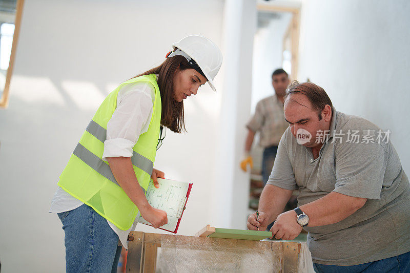 女工程师正在建筑工地和工人们谈话。