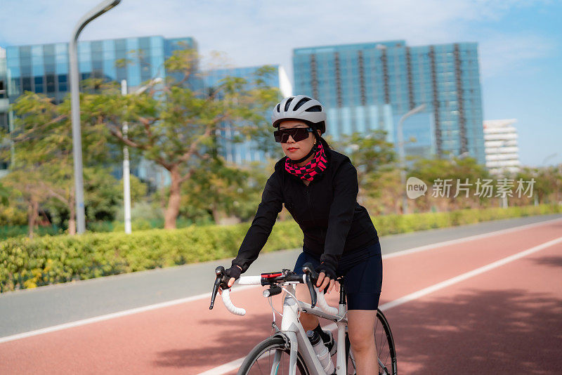 在城市公园路上骑公路自行车的女人