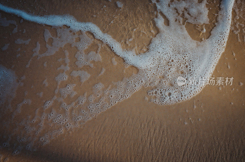 神奇的光:一个温柔的海浪在海滩上的特写