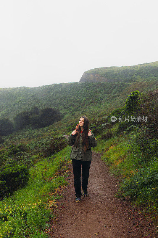 一个快乐的女人走在山上，可以看到旧金山的金门大桥