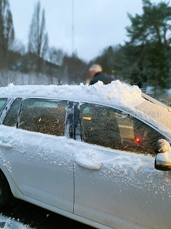 一名男子正在清除汽车上的积雪