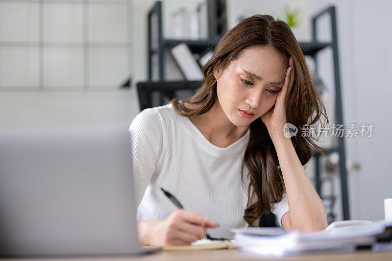 一位女商人在家庭办公室专注于工作时，看起来压力很大，而且头痛。