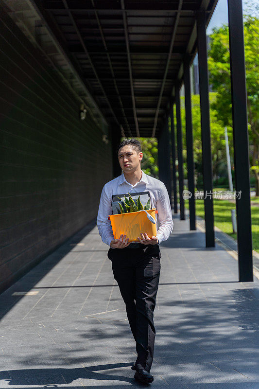 一名中国男子在被裁员后拿着自己的行李