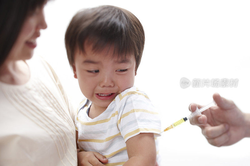 母亲抱着哭泣的男婴，他正在接种疫苗