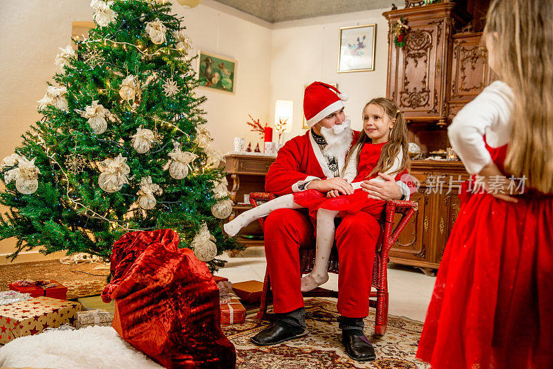 一个家庭成员和两个小女孩装扮成圣诞老人