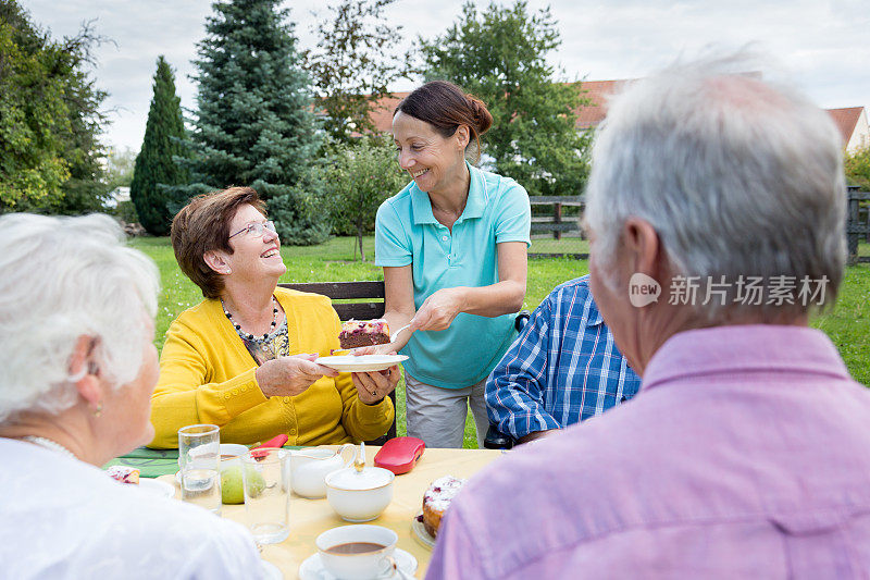一群老人坐在花园的桌子旁