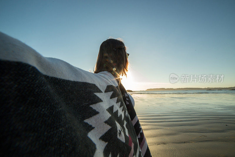 在海滩上欢呼的年轻女子张开双臂――夕阳
