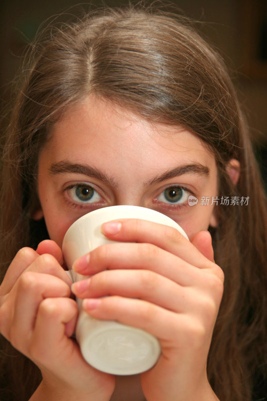 从咖啡杯后面窥视的年轻女人的眼睛