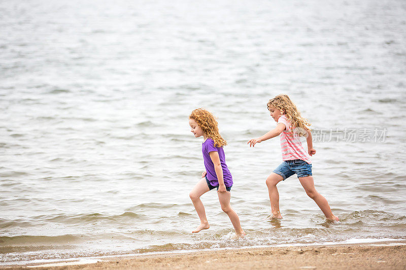 两个小女孩在海滩的水里奔跑