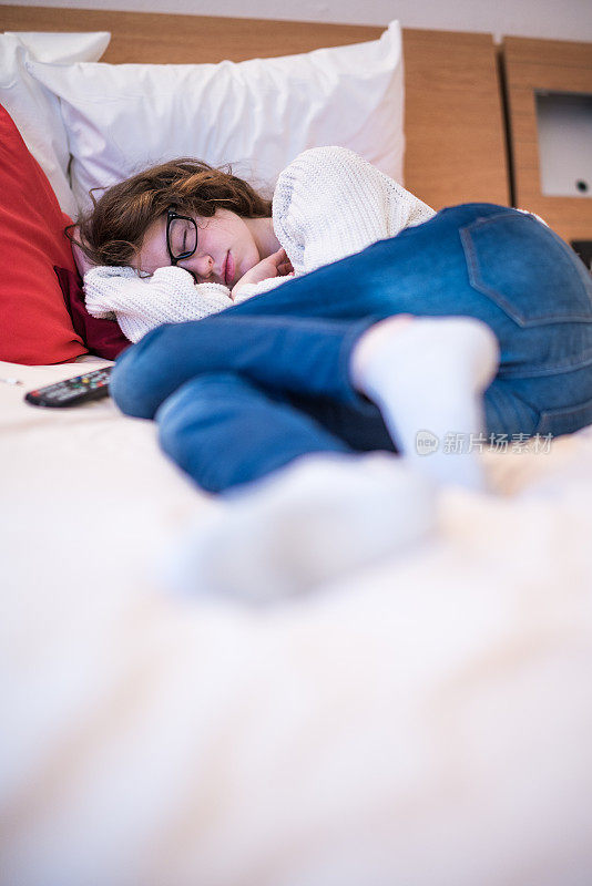 长头发的漂亮的16岁少女在旅行期间睡在酒店房间的床上