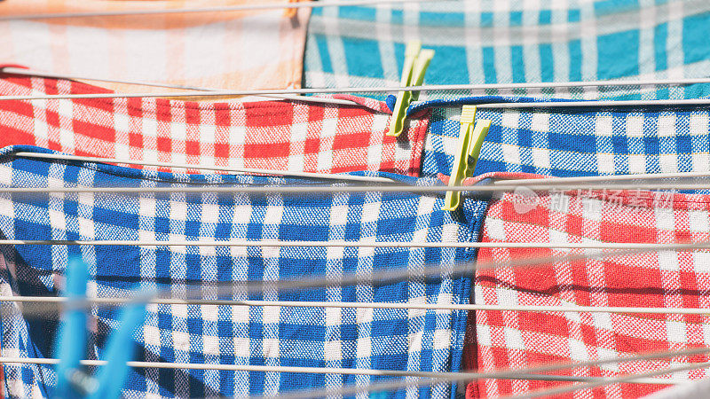花园里的晒衣绳上晒着毛巾、方形图案的多色餐巾