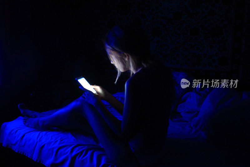 年轻女性在睡前使用智能手机