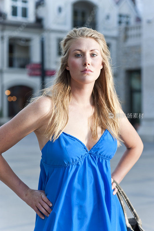 年轻漂亮的金发女人穿着蓝色的衣服在户外购物中心