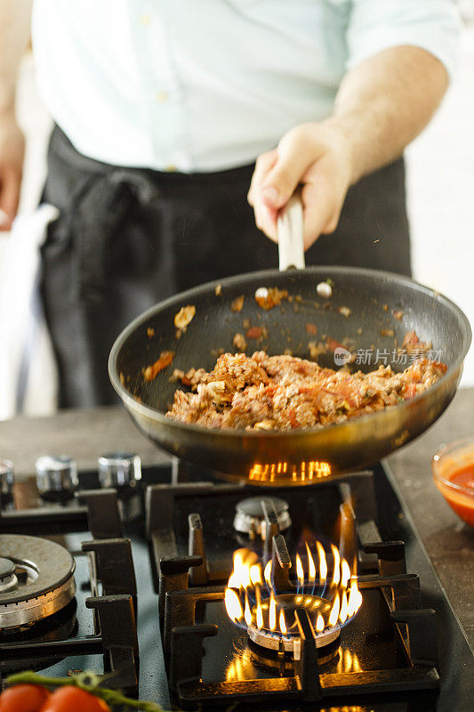 厨师在煤气炉上烹饪意大利肉酱面