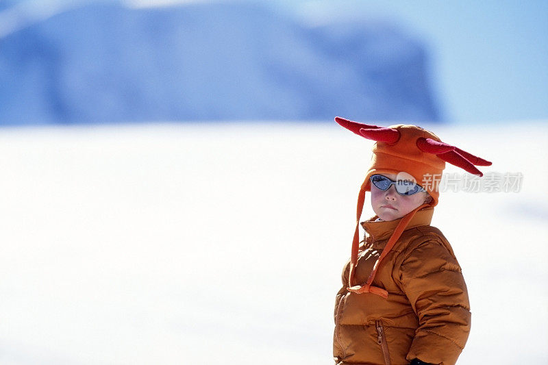 小男孩在雪地里展示他的滑雪服