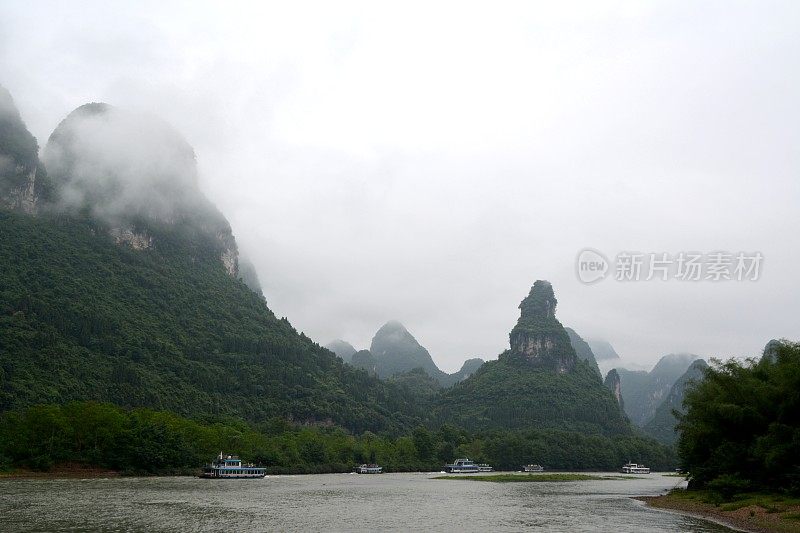 漓江映衬着苍翠的山脉和雾蒙蒙的天空。