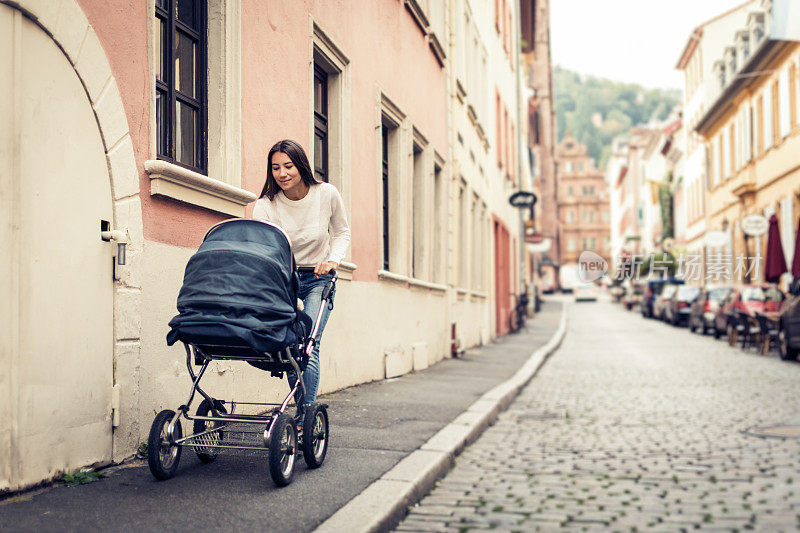 年轻的母亲推着婴儿车在城市里