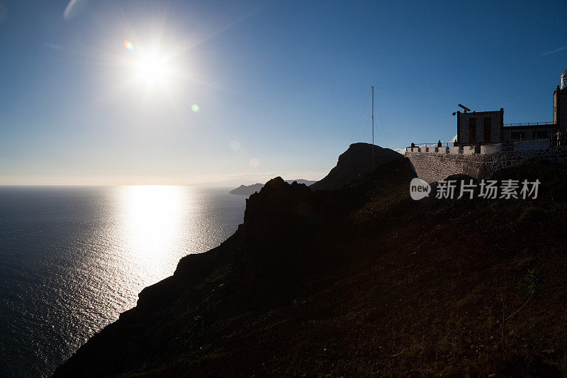 落日掠过平静的海面，灯塔和加那利群岛富尔特文图拉岬的剪影