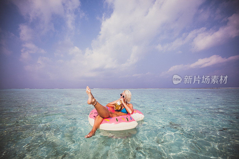 一个金发女人在马尔代夫的海上漂浮在充气甜甜圈上