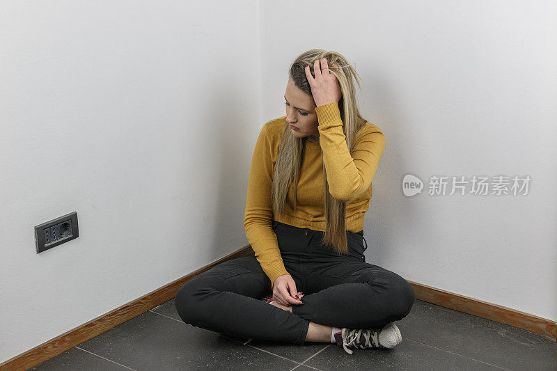 漂亮年轻沮丧的女孩坐在地板上