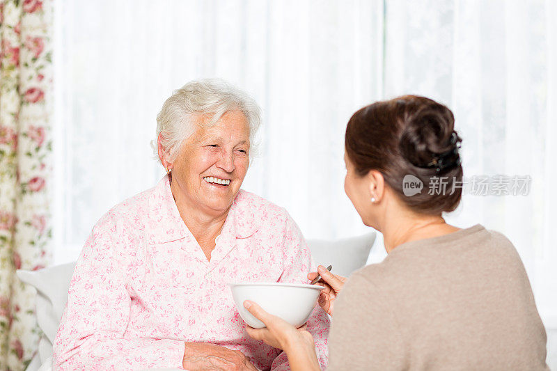 家庭护理护士与老年病人在床上吃午饭