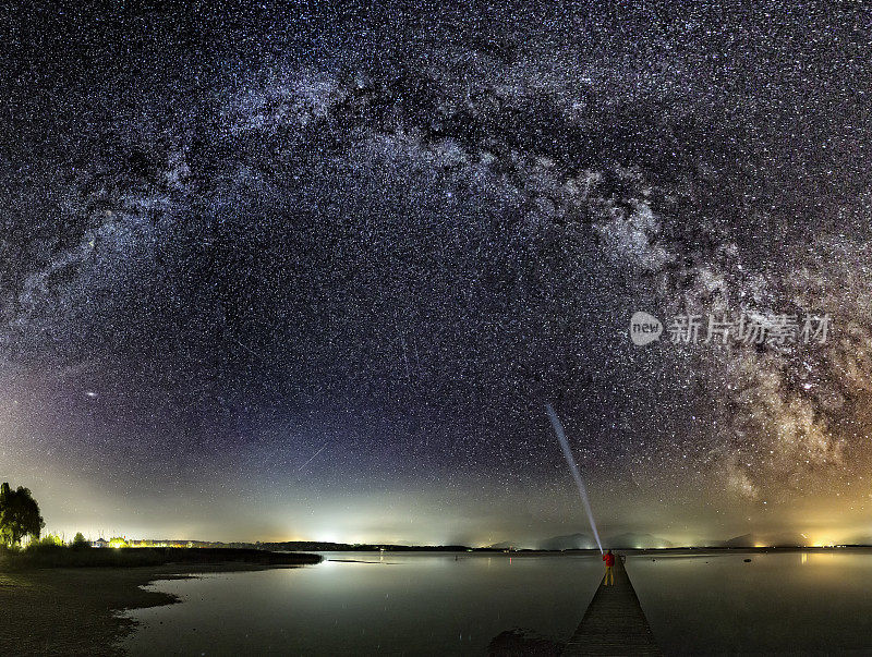 Jetty上的一名男子在Chiemsee湖享受银河