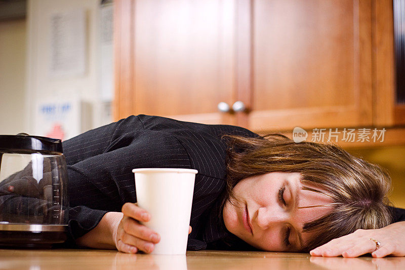 一个女人拿着一个白色的塑料杯睡在木地板上